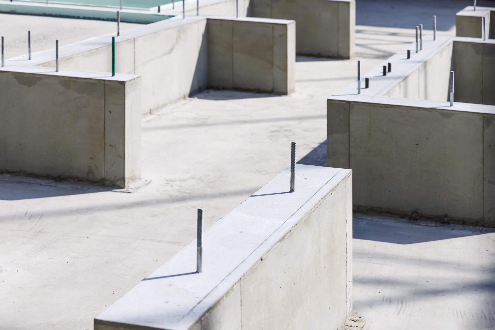 Concrete foundation of a building under construction; gray blocks with vertical metal rods.