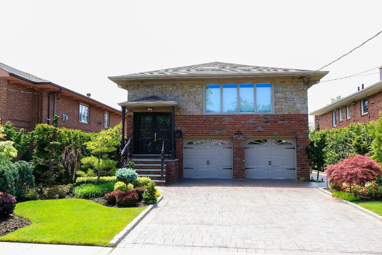 Two-story house with a brick facade and two-car garage. Green lawn and landscaping. Driveway.