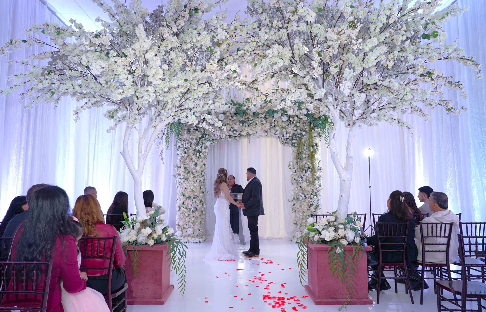 A bride and groom are getting married in front of a crowd of people at a wedding ceremony.