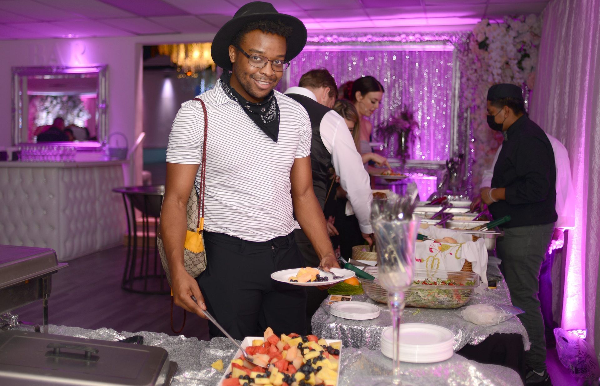 A man is standing in front of a buffet table holding a plate of food.