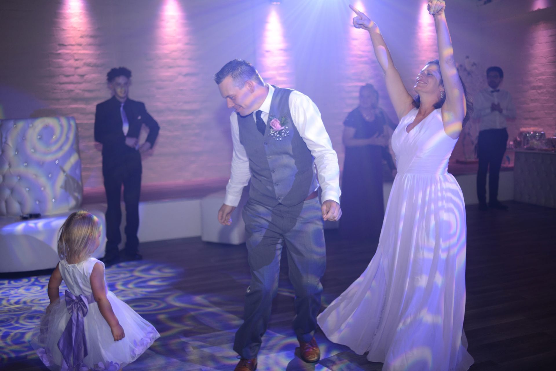 A bride and groom are dancing with a flower girl at their wedding reception.