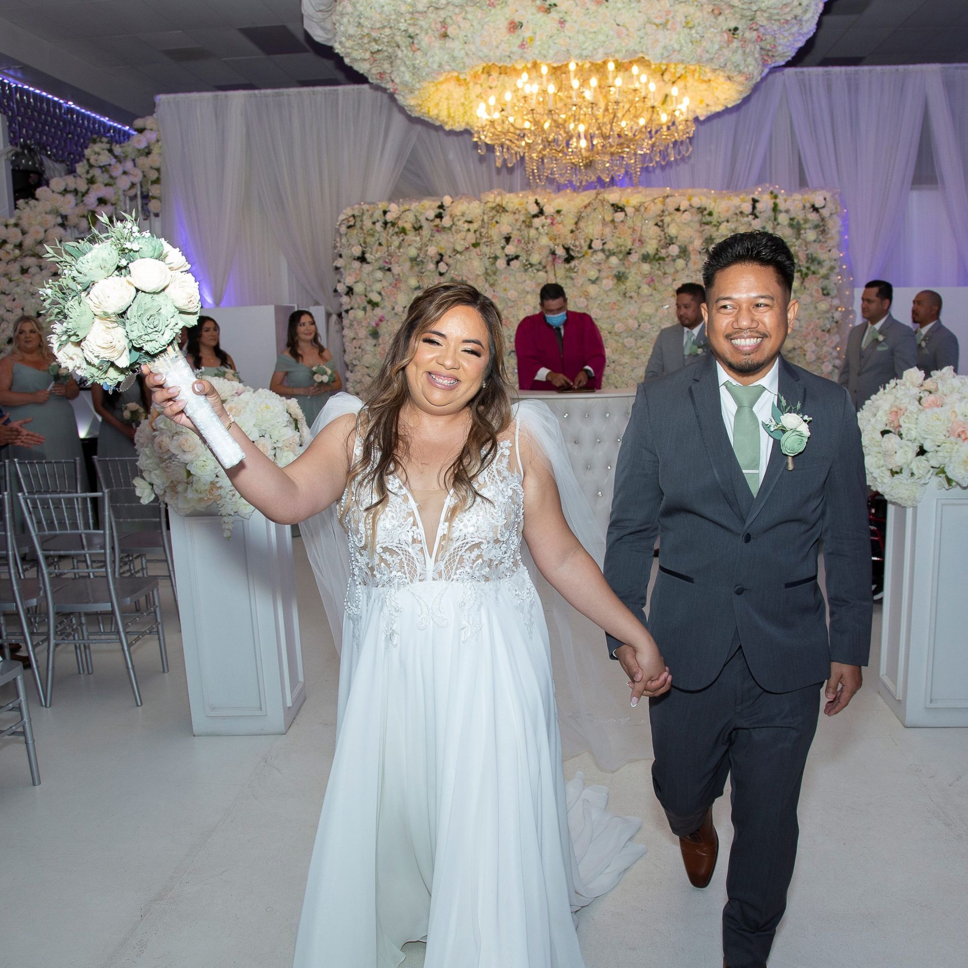 A bride and groom are walking down the aisle holding hands