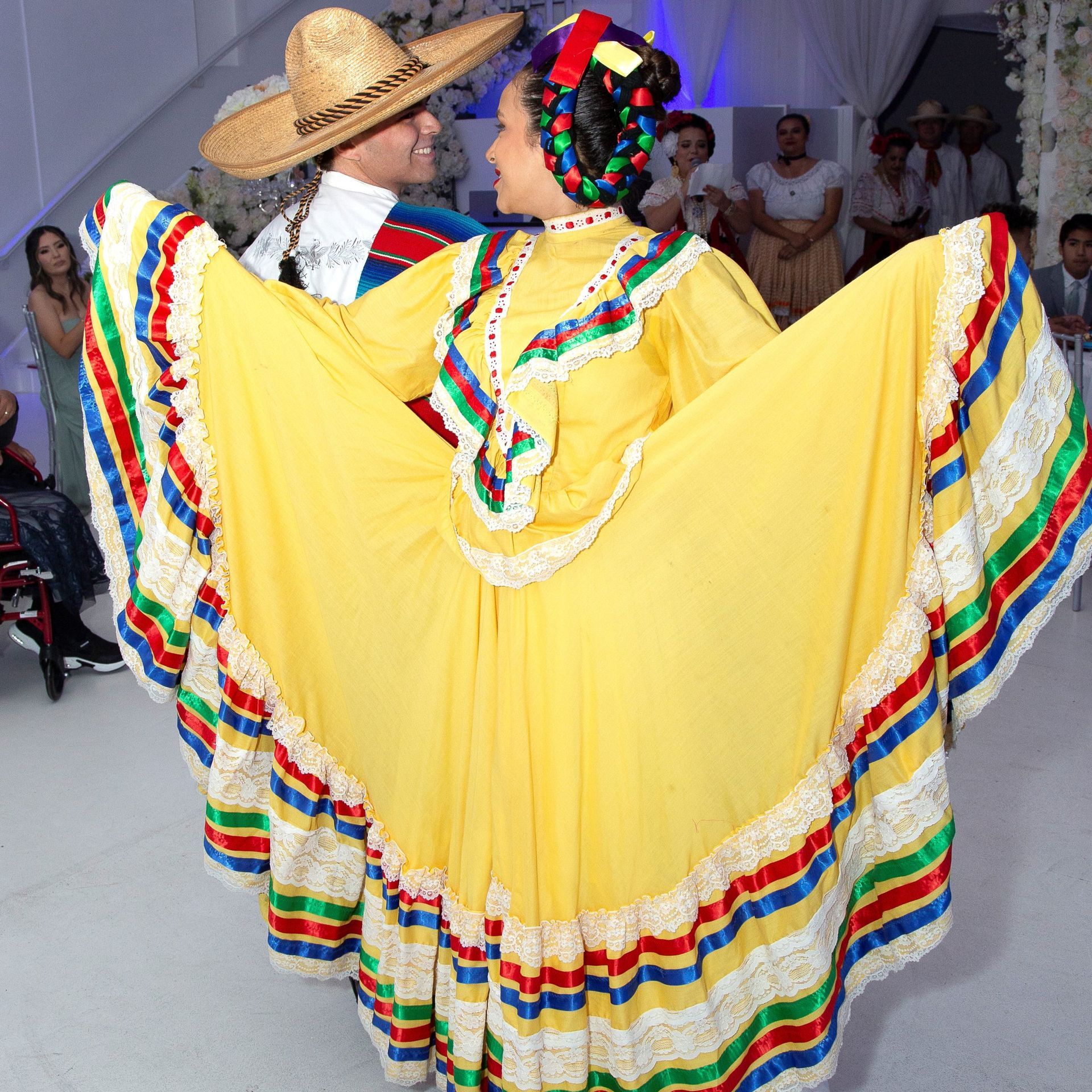 A woman in a yellow dress is dancing with a man in a sombrero