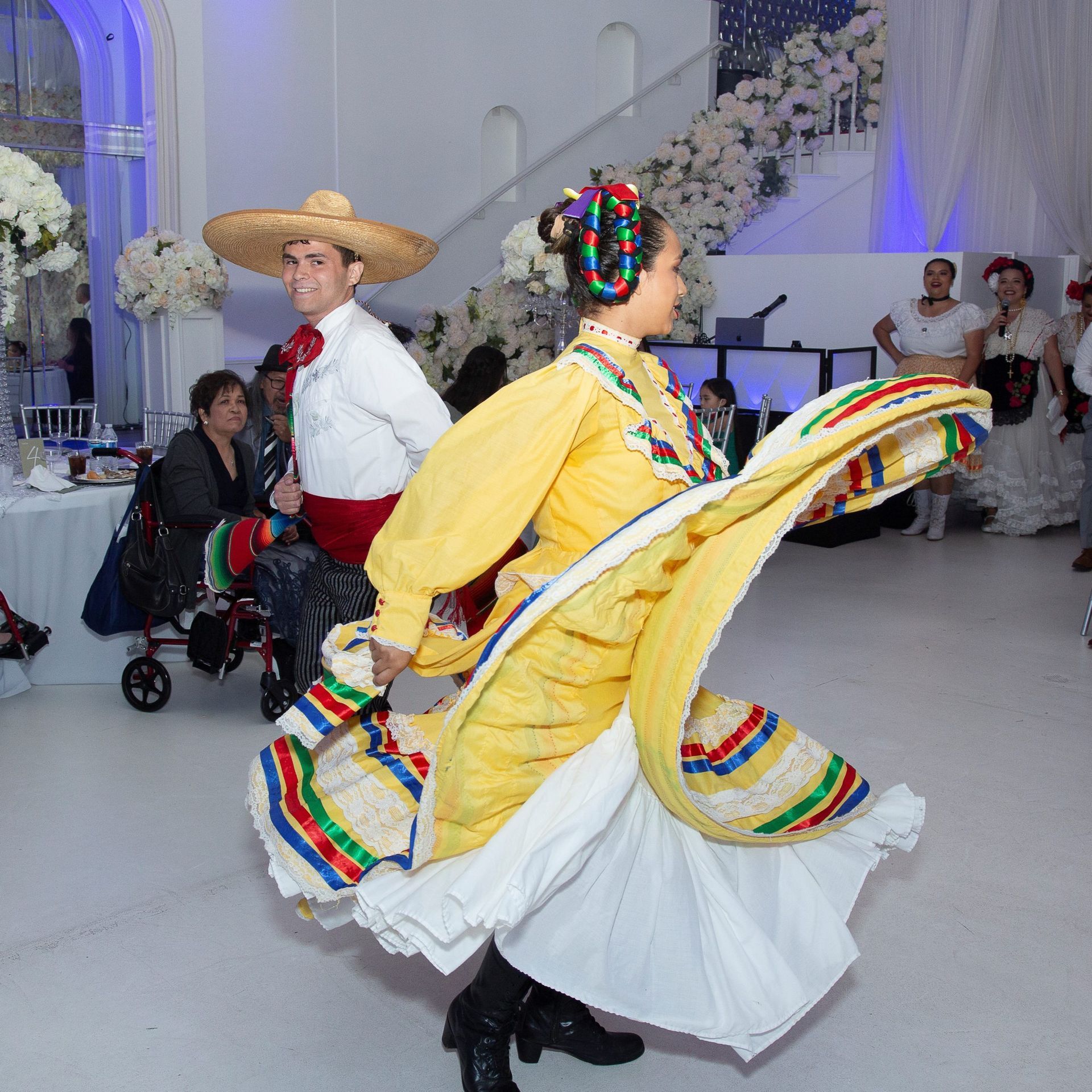 A woman in a yellow dress is dancing with a man in a sombrero