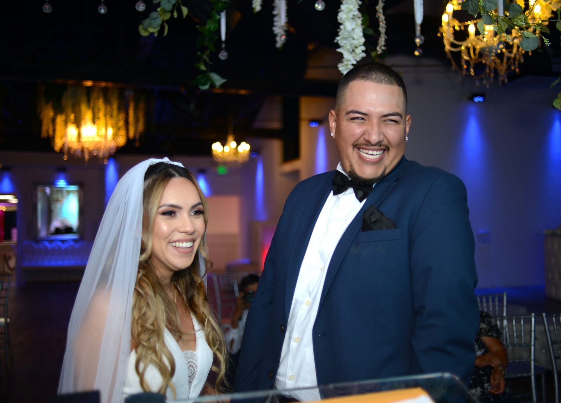 A bride and groom are posing for a picture at their wedding reception.