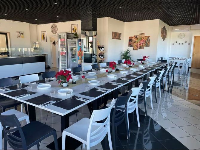 Tavolo apparecchiato in un ristorante luminoso con sedie bianche e centrotavola di stelle di Natale rosse.