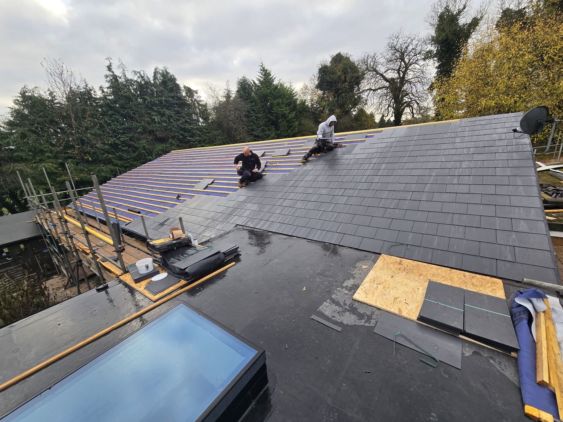 Two men are working on the roof of a house.