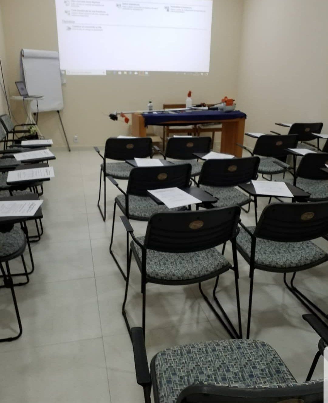 Uma sala de aula com mesas e cadeiras e uma tela de projetor