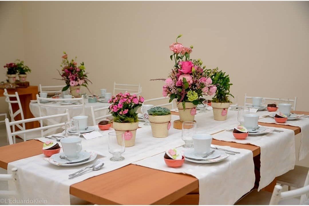 Uma longa mesa com pratos, xícaras e vasos de flores.