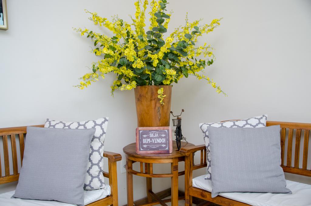 Duas cadeiras e uma mesa com um vaso de flores sobre ela.