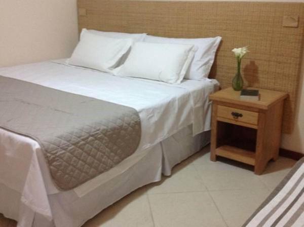 Um quarto com uma cama e uma mesa de cabeceira com um vaso de flores