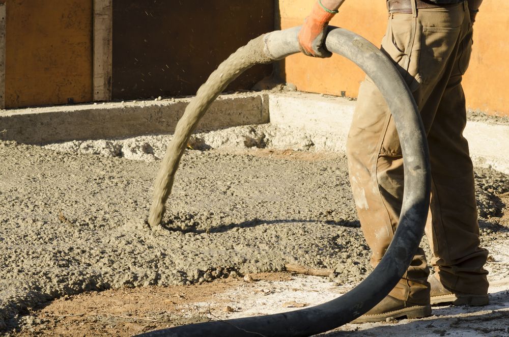 Person Pouring Concrete From a Hose Onto a Construction Site — Far Northern Concrete Pumping in Croydon, QLD