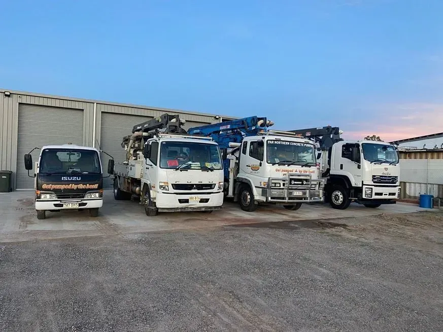 Four White Trucks Parked in Front of a Gray Building — Far Northern Concrete Pumping in Mareeba, QLD