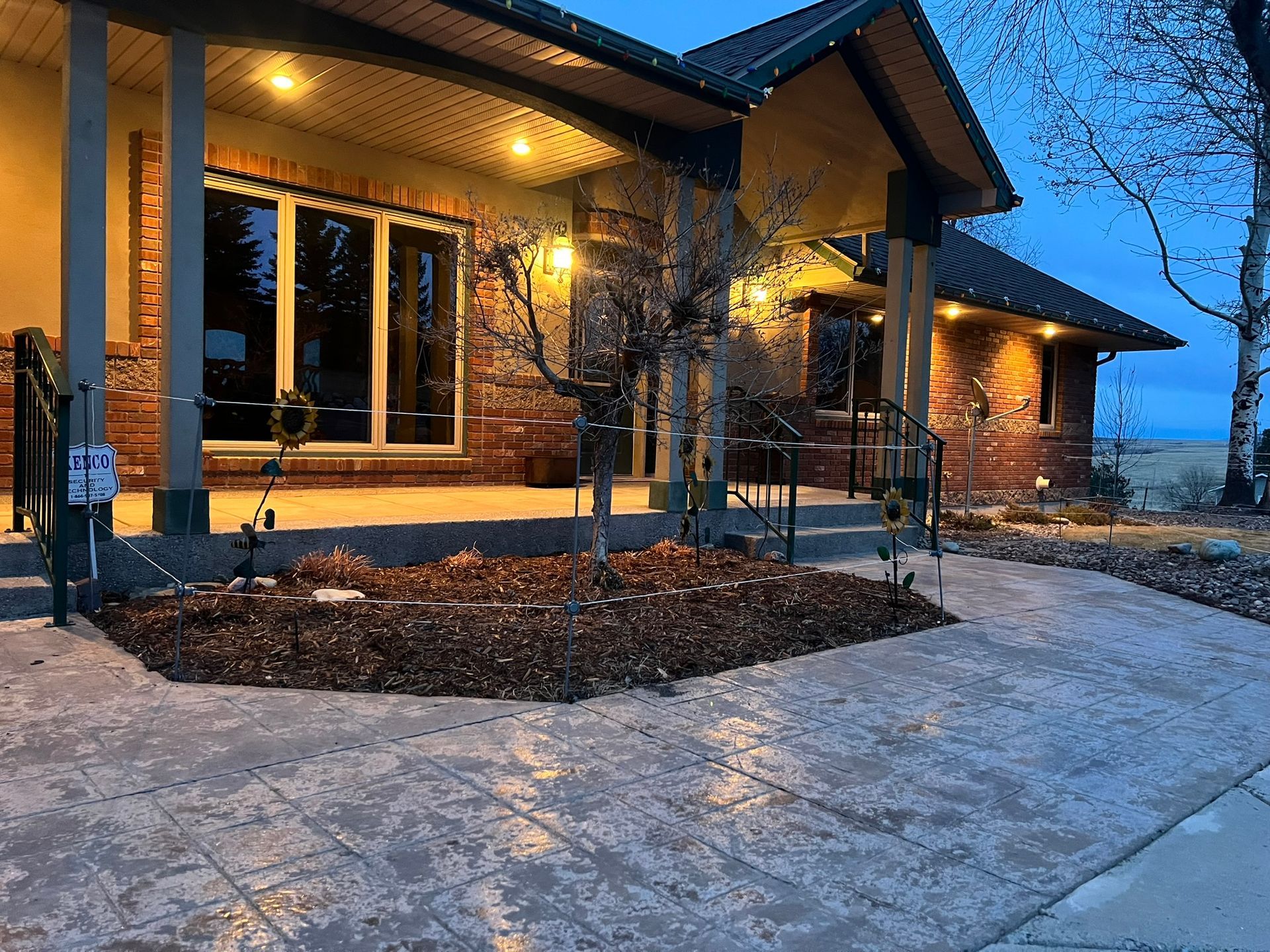 House exterior with brick and stone facade, lit up with warm lights. Pathway in front.
