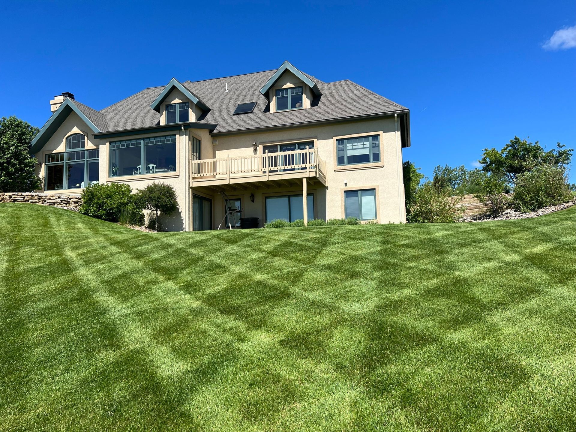 House on a hill with a diamond-patterned lawn; blue sky.