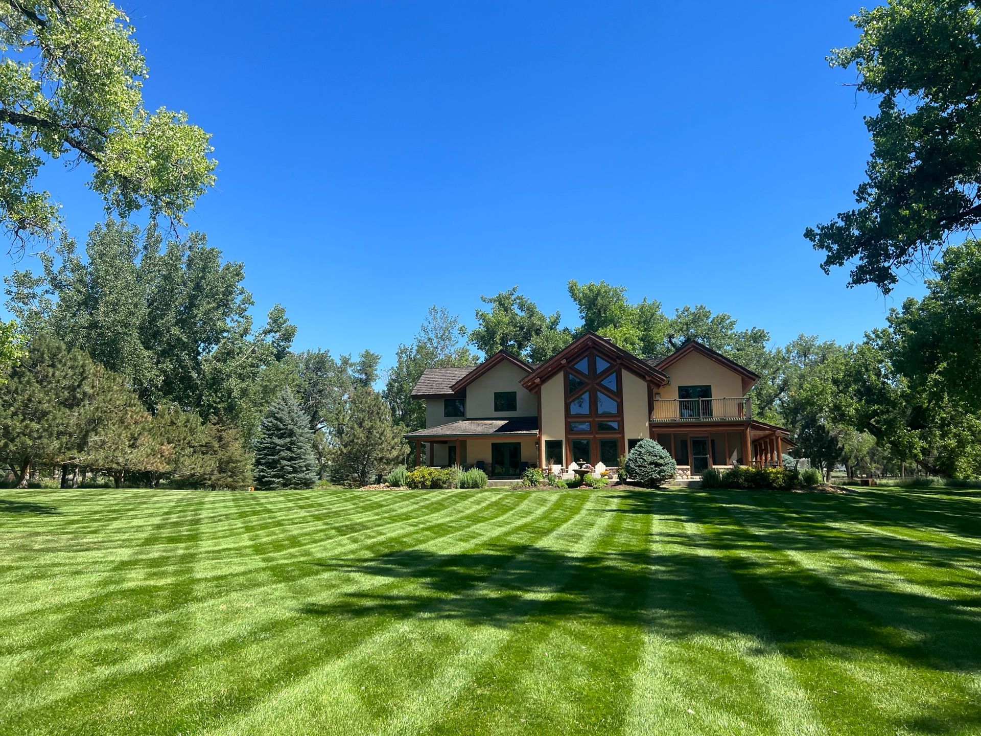 Large house with a well-manicured lawn under a clear blue sky.