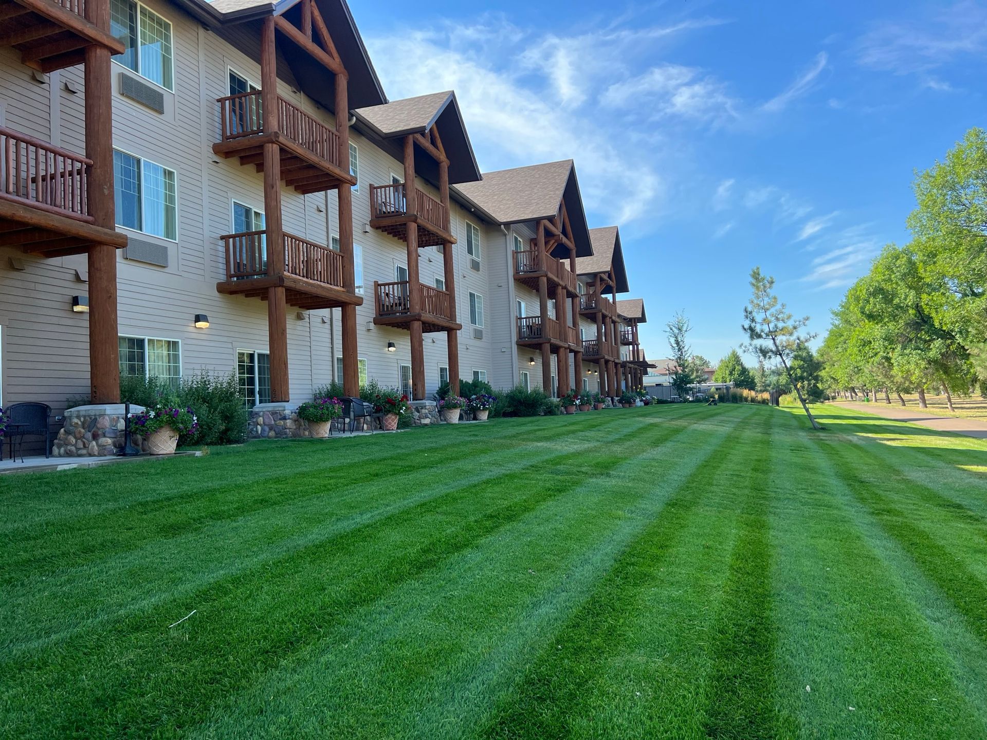 Hotel with brown balconies and manicured green lawn under a blue sky.