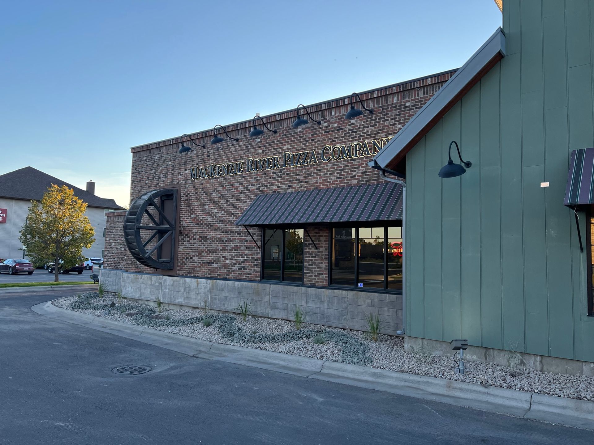 Brick building with a large water wheel and green siding. Blue sky in the background.