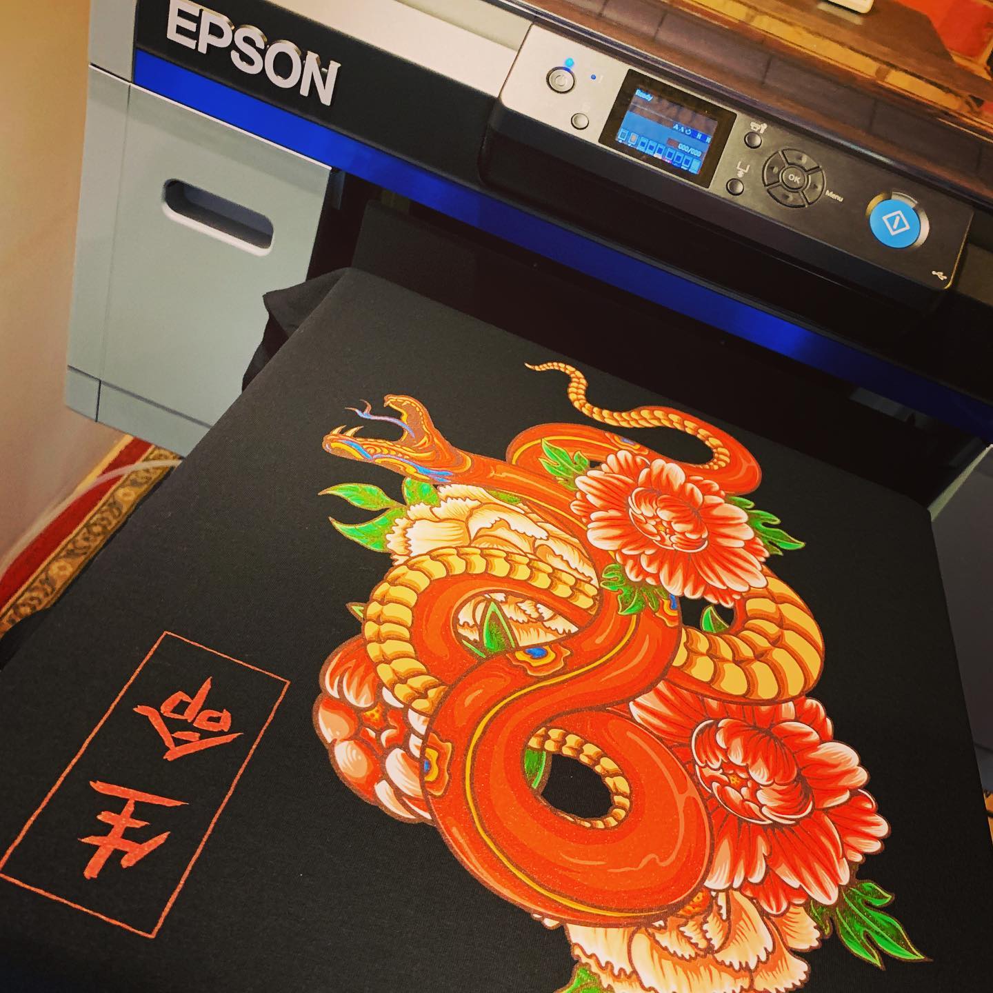 Epson SC-F2160 DTG printer with a print example on a black t-shirt.