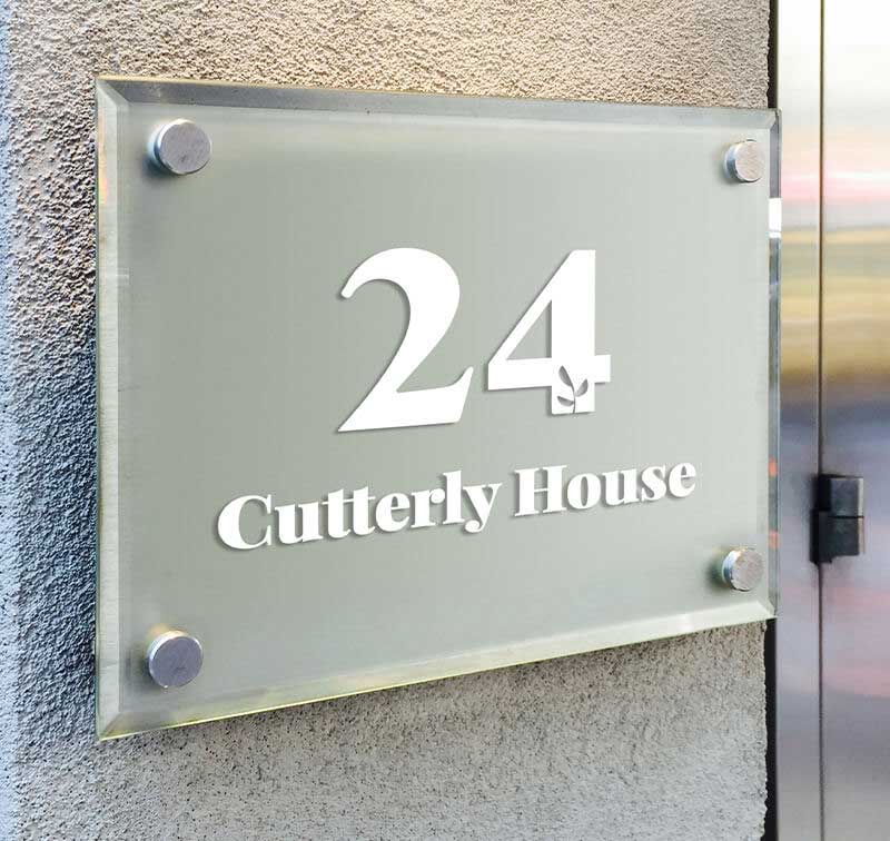 glass sign bolted to the front of a building with numbers and letters