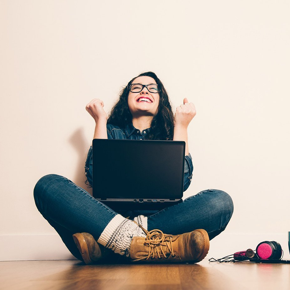 Happy woman sitting cross legged with a laptop