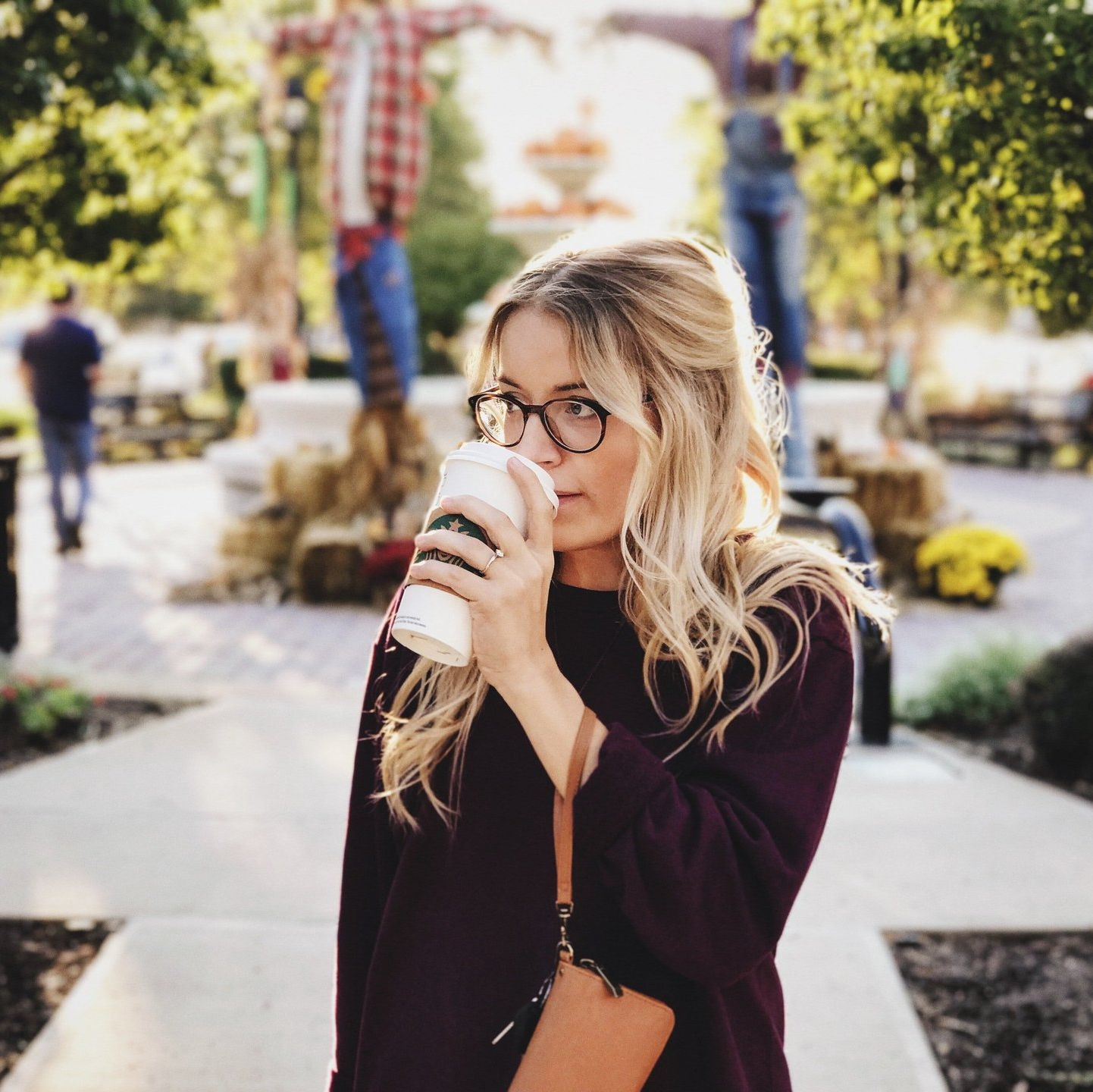 Woman standing outside drinking coffee.