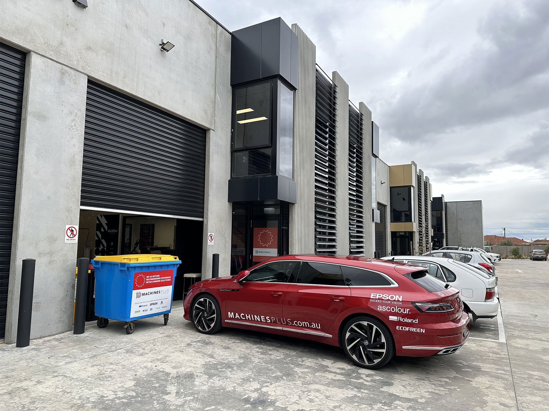 Machines Plus warehouse with red car out the front