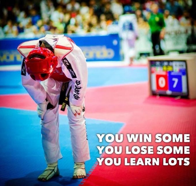 Due atleti di taekwondo si allenano su un tatami ben illuminato, uno con l'abbigliamento rosso e l'altro con quello blu.