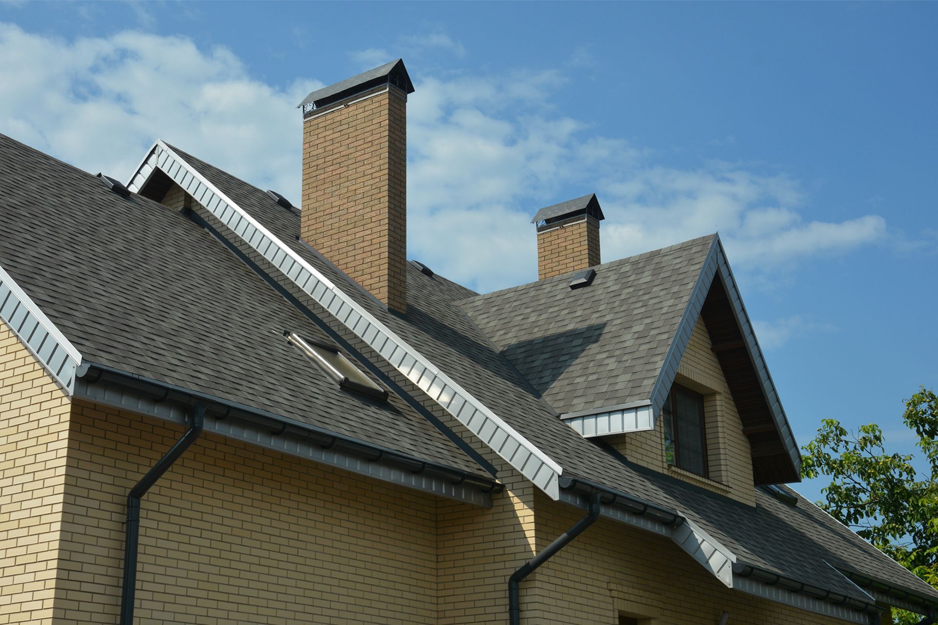 A multi-story residential building with light-colored horizontal and vertical siding, brown shingled roofs, and clear sky.