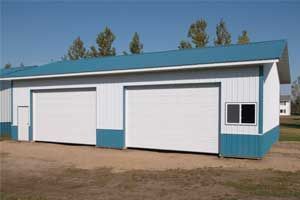 White and teal metal garage with two doors and a window, under a blue sky.