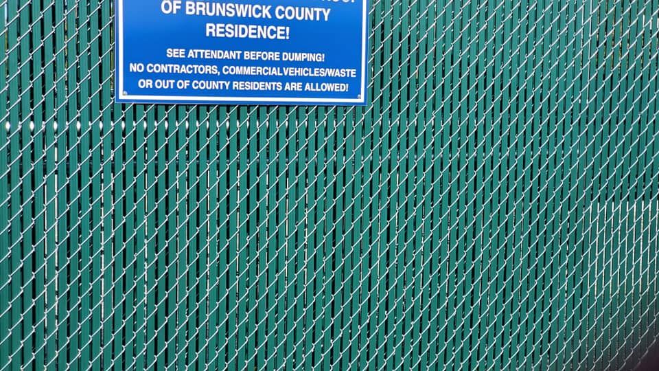 A green chain link fence with a sign that says Brunswick County Residence