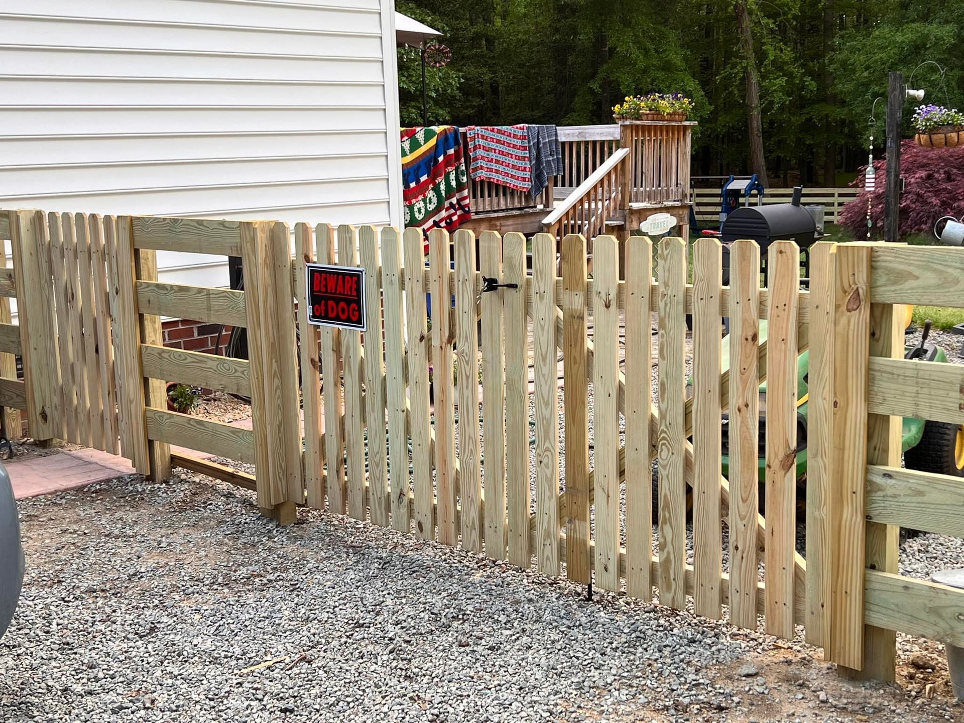 A wooden picket fence with a gate in front of a house.