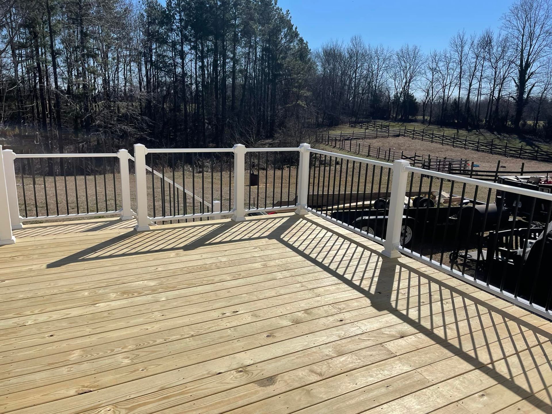 A wooden deck with a white railing and trees in the background.