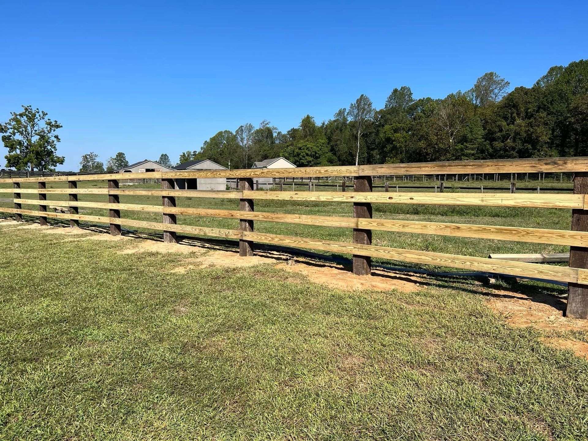A wooden fence is in the middle of a grassy field.