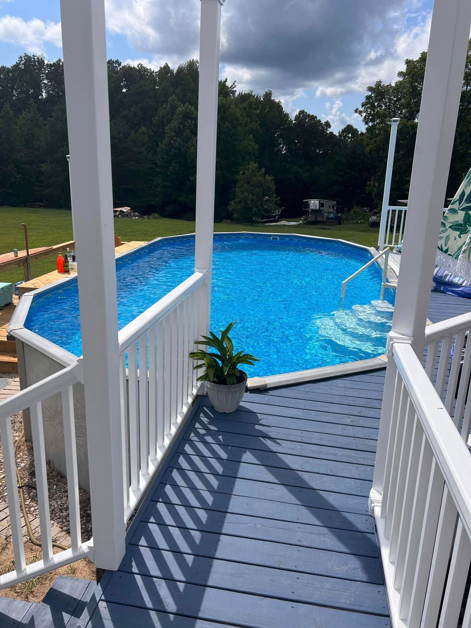 A large swimming pool is surrounded by a white railing on a deck.