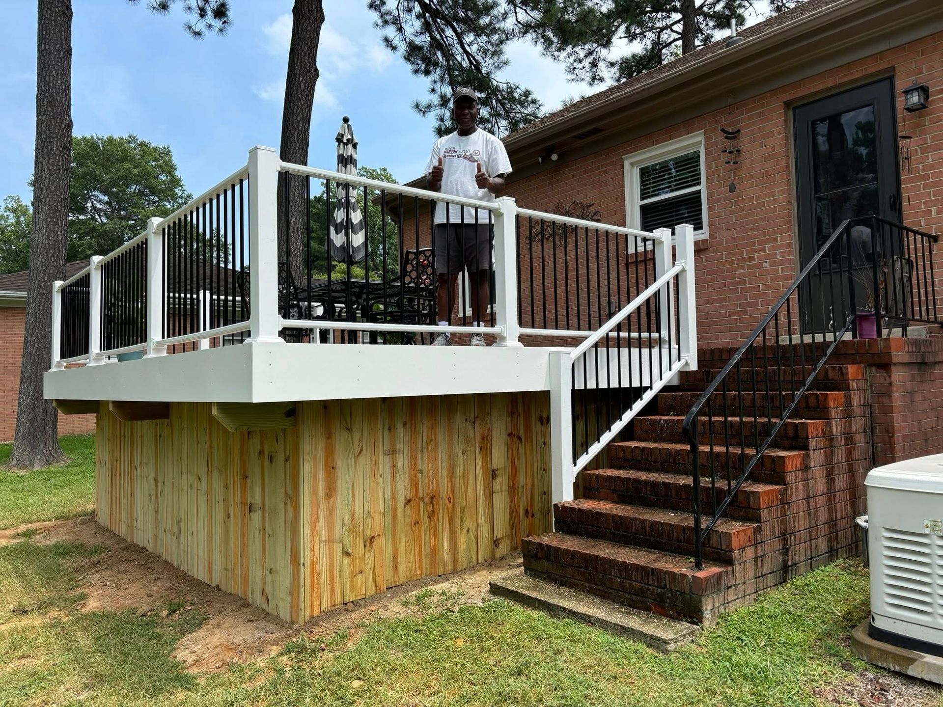 A man is standing on a deck in front of a house.