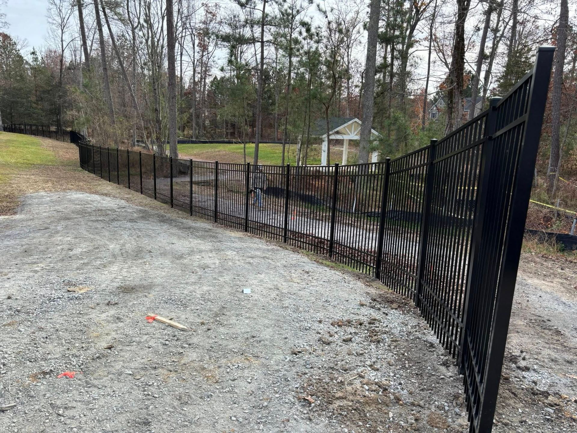 A black metal fence is along the side of a gravel road.