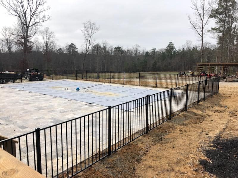A fence around a swimming pool with a blue cover on it.