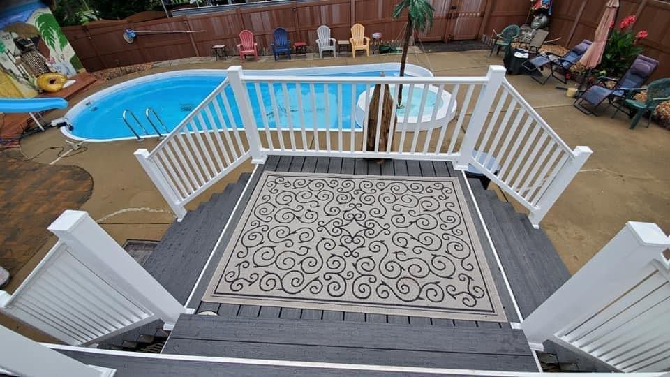 A large swimming pool is surrounded by a white railing on a deck.