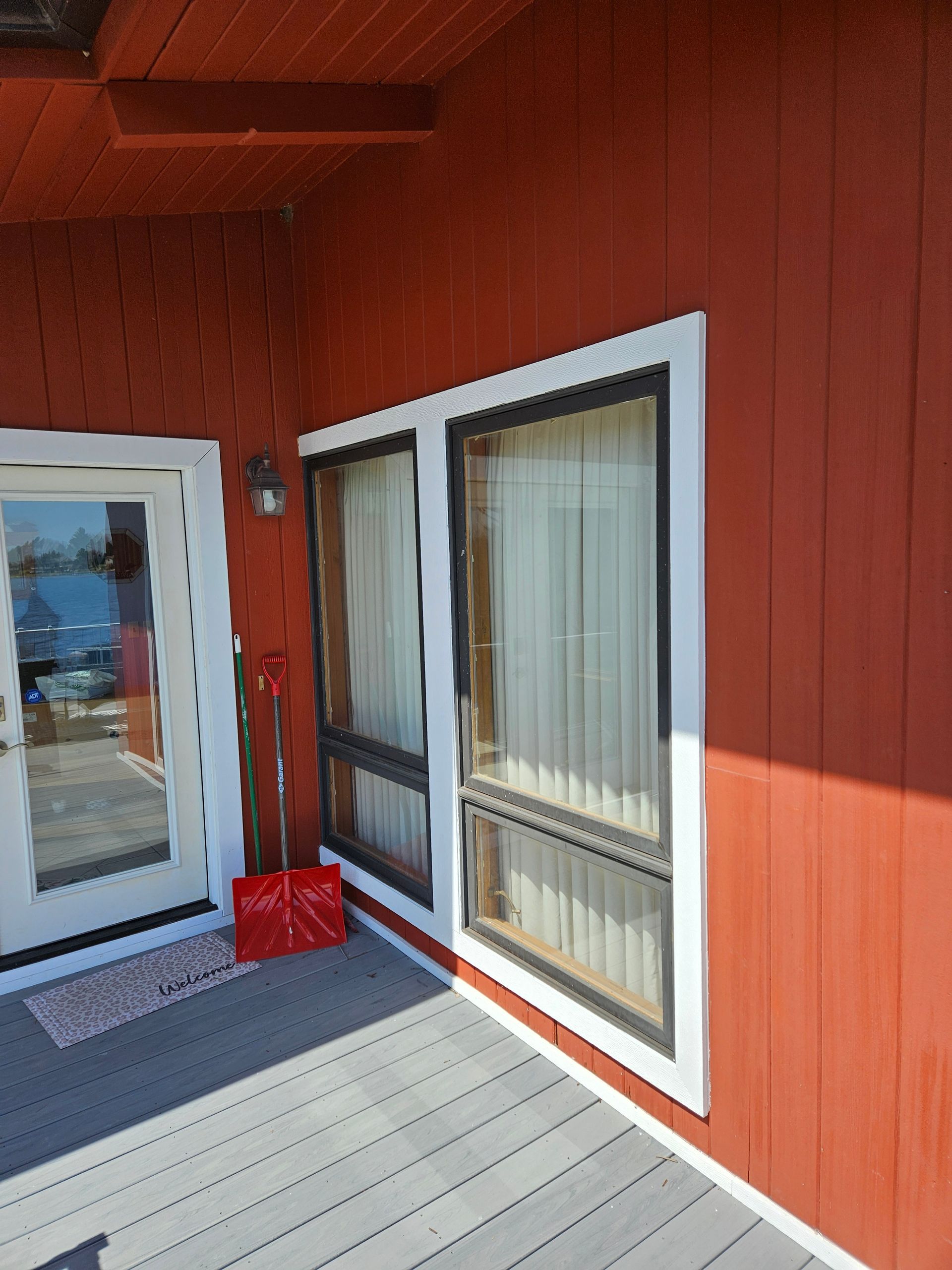Red exterior porch with glass door, large window, and a red snow shovel by the entrance.