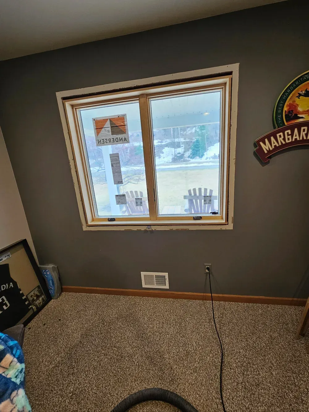 Small carpeted room with a window, dark walls, and a wall sign near the corner.