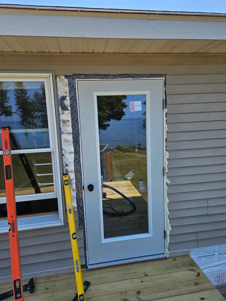 Exterior door installation on a house with siding, level and ladder beside the doorway