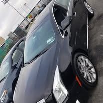 Black limousine parked on a white salt flat with mountains in the background under a clear blue sky.