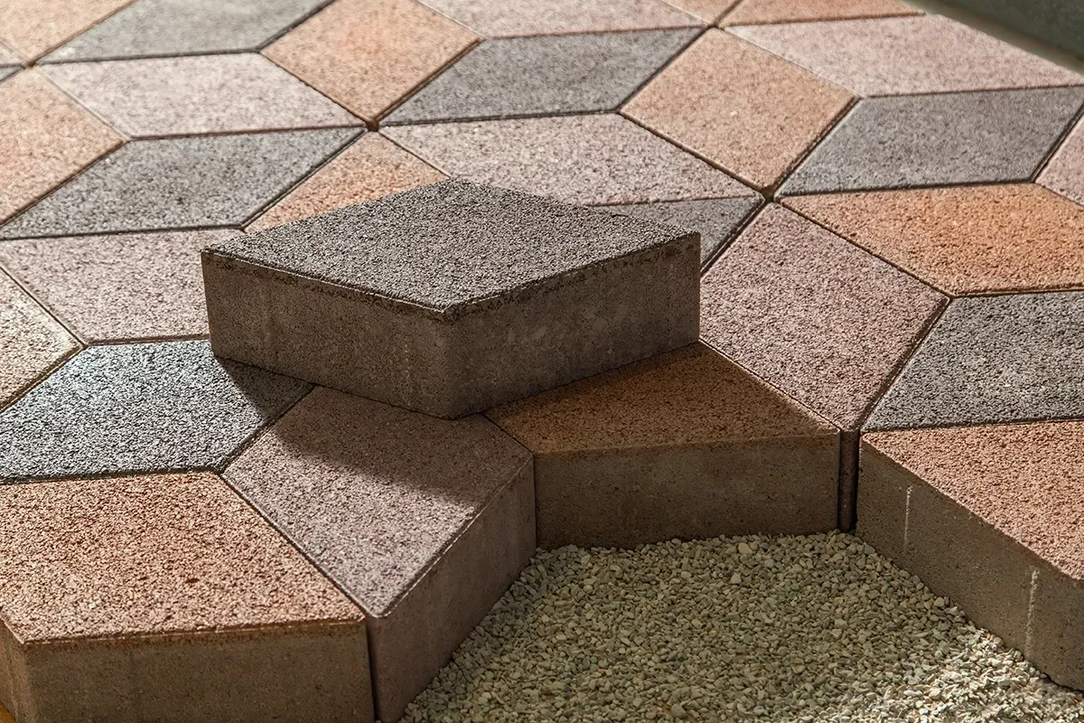 Close-up of diamond-shaped paving stones in various colors, one stone is placed on the others.