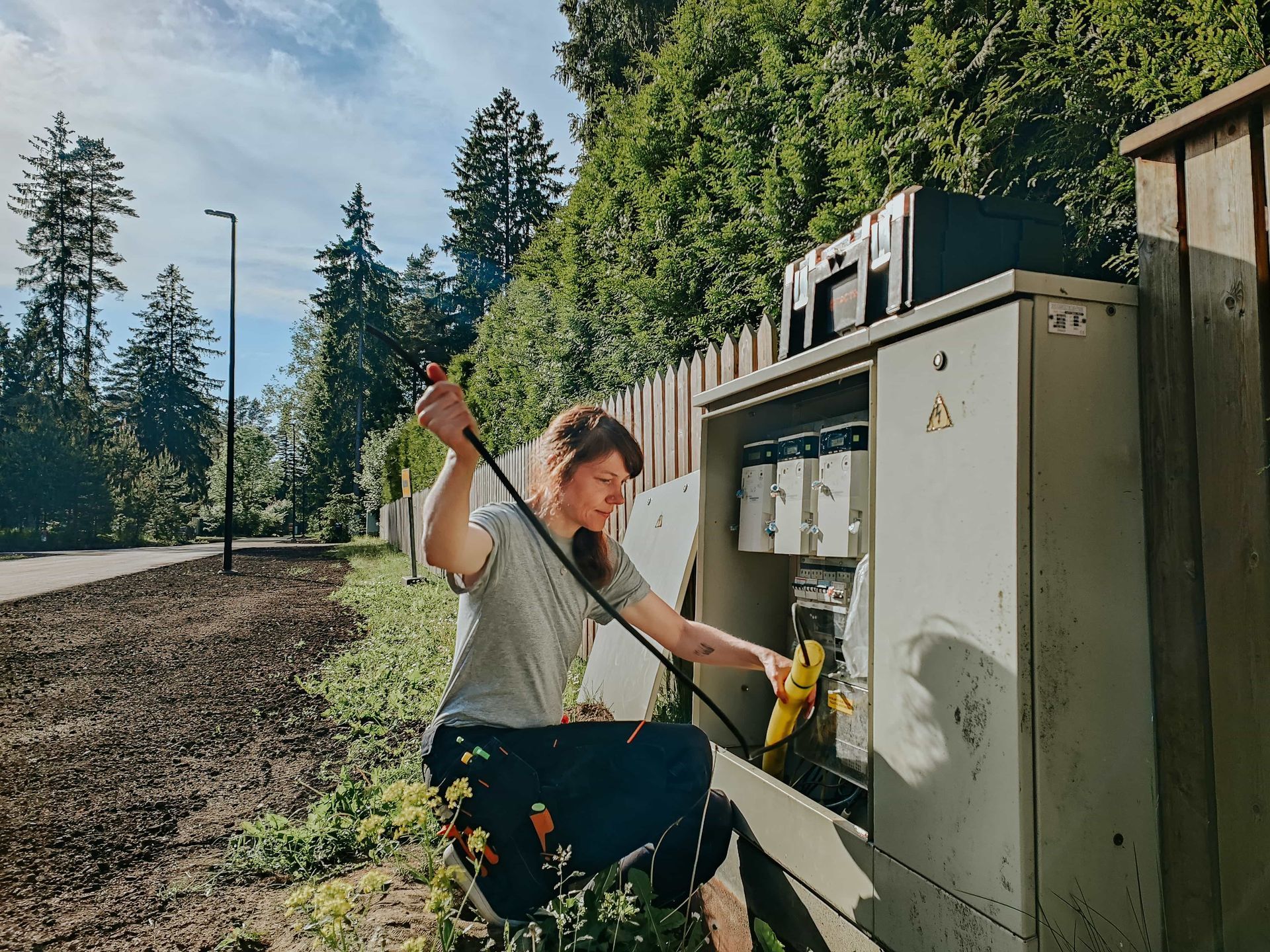 A woman is kneeling down next to a box with a screwdriver.