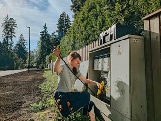 A woman is kneeling down next to a box with a screwdriver.