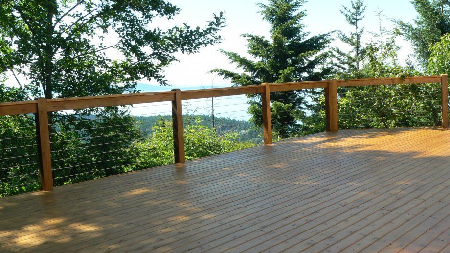 Wooden deck with railing overlooking a view of water and trees.