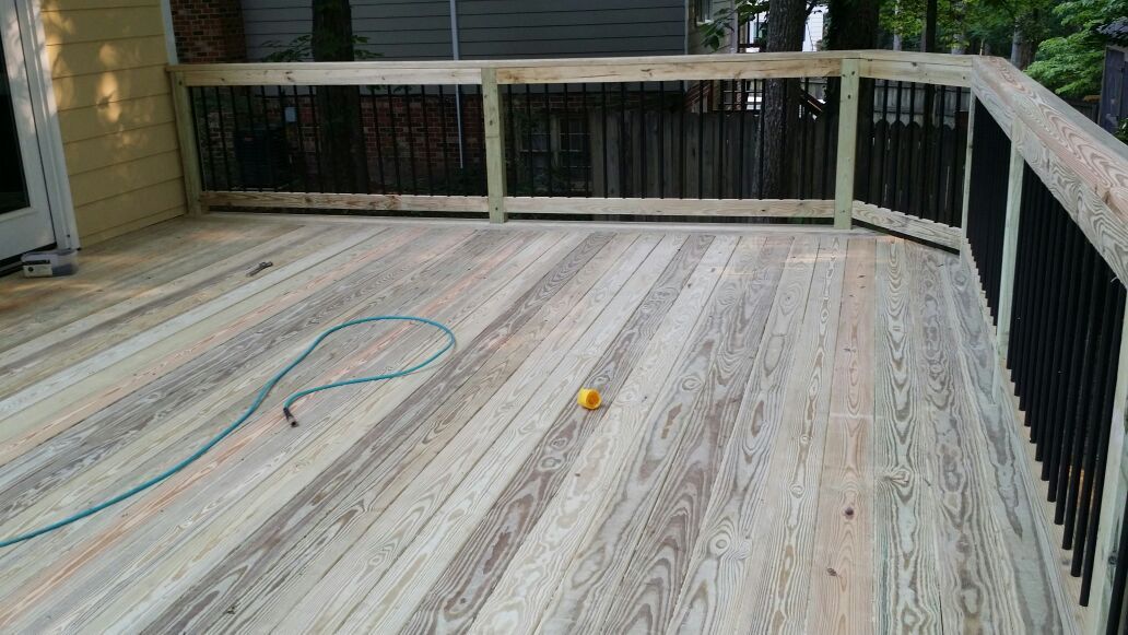 Wooden deck with black railings and a yellow ball.