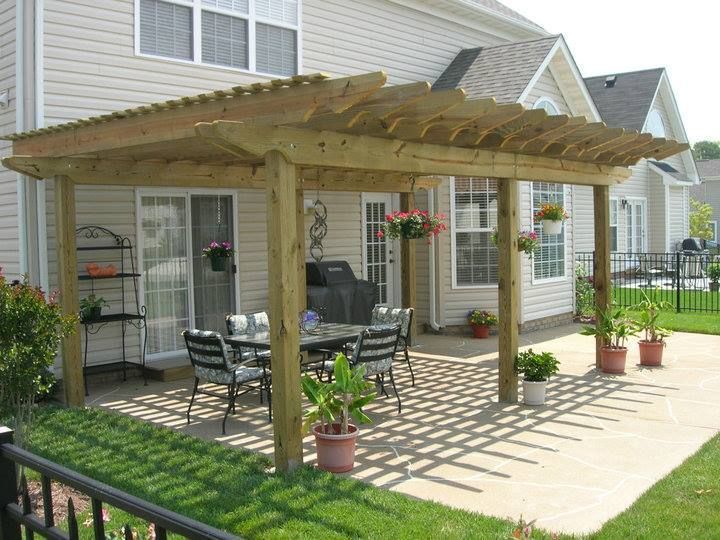 Wooden pergola over patio with outdoor dining set, plants, and sunny backyard.