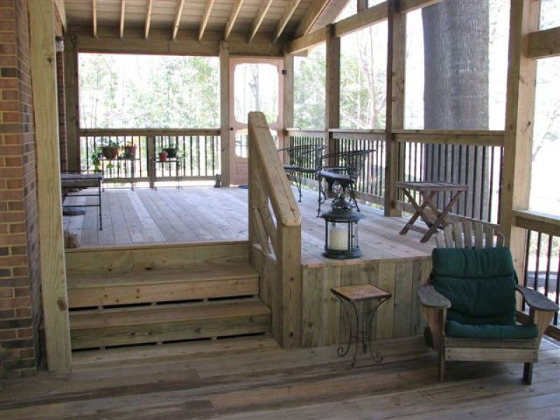 Wooden screened porch with steps, railing, furniture, and candle lantern.